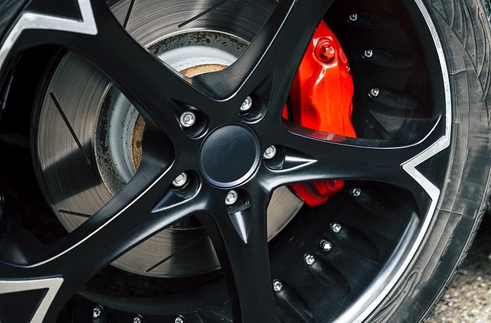 Red brake pads and discs of modern car with black alloy discs
