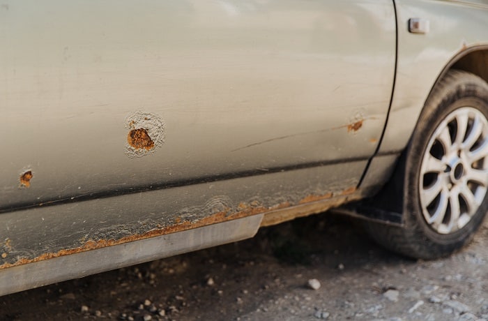 Car door with rust and metal corrosion. Need repairs, road salt damage.