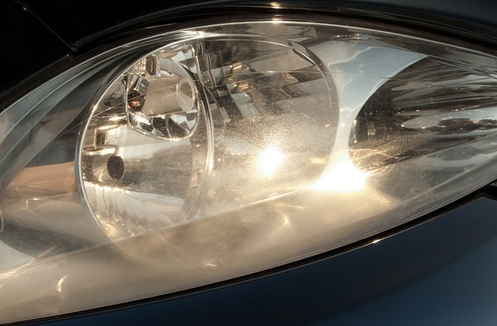 Damaged and blurred headlight surface as a result of weather condition and aging of a car.